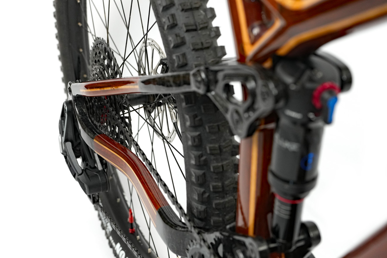 Sculptured rear stays of a custom wooden HTech mountain bike, showcasing deep wood grain color and high gloss finish